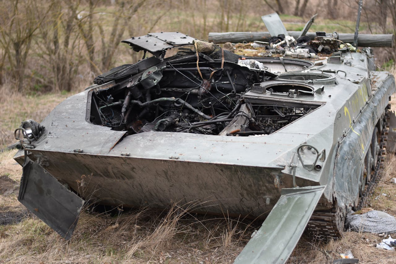 Close-up of a destroyed military tank in an outdoor setting, emphasizing war's impact.