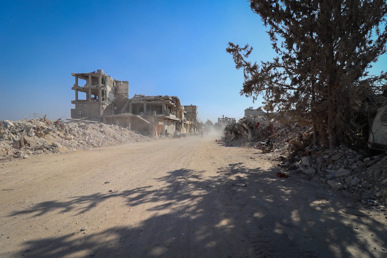 services-02 Devastation in Idlib, Syria with destroyed buildings and debris under a clear sky.